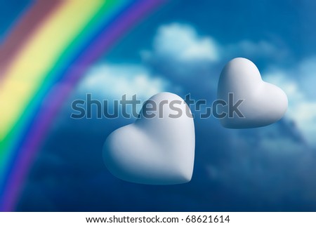 Rainbow and two hearts against a blue sky background