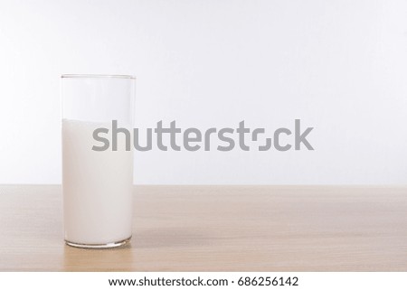 Glass with milk standing on table against plain background