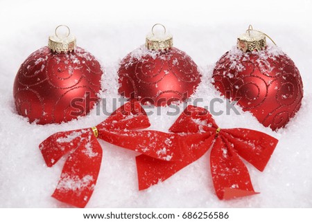 Christmas background with a seasonal ornament, red decorations, and snow