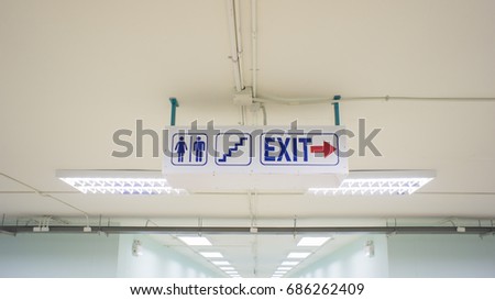 Signs to the toilet and exit inside the building.