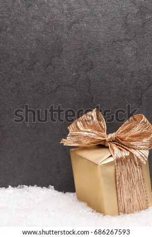 Christmas greeting card. Noel festive background. New year symbol. Gold gift box on snow. Festive background with copy space.