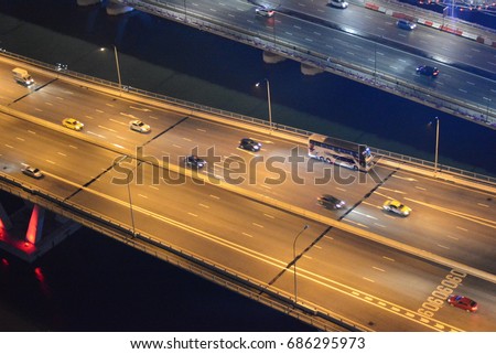 A view of toll way from the building at night that had different types of transportation such as car, truck, bus move with the speed across the bridge