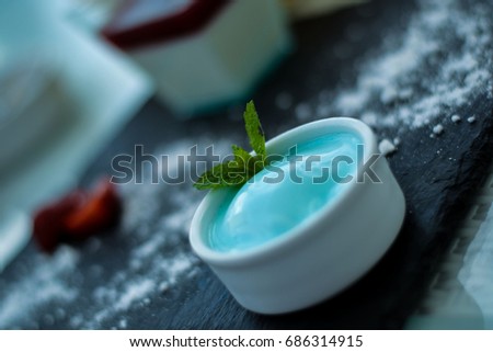 Delicious blue ice-cream with mint leaf on black plate