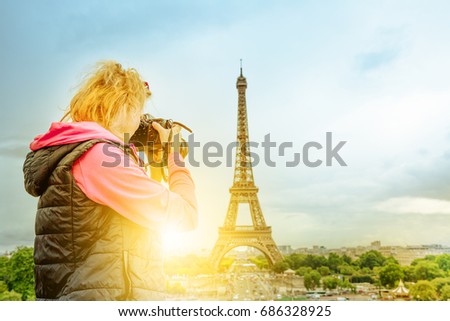 Professional photographer with camera on Place du Trocadero takes shot of Tour Eiffel at sunset. Traveler woman in Paris, France, Europe. Eiffel Tower on blurred background. Travel and tourism concept