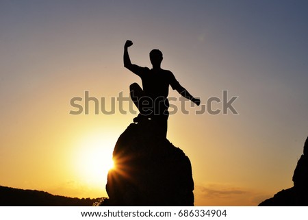 Man raised hand on top of the mountain to celebrate success at sunset. Men on the top of the steep rock
