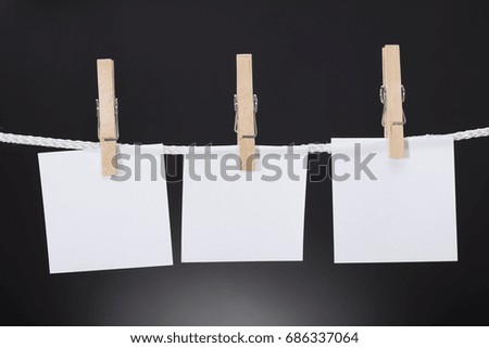 Closeup of white paper cards hanging on rope attached with clothespins against black background