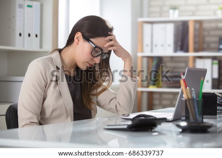 Depressed Young Businesswoman Sitting At The Table On Her Workplace In Office