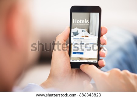 Close-up Of A Person Holding A Smart Phone Using Online Low Prices Hotels Application