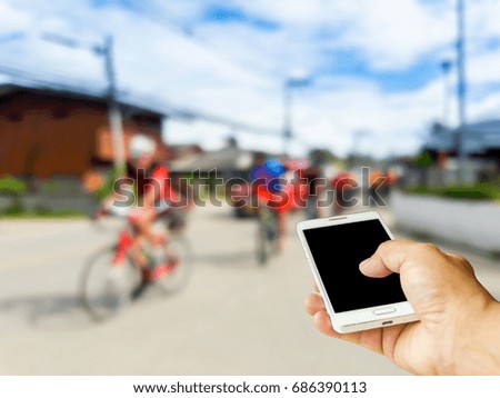 Man use mobile phone, blur image of rural cyclists as background.