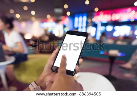 Hands holding blank white screen smart phone in front of the movie theatre, Hands holding smart phone to use for online booking ticket.