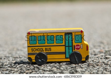 Yellow wooden school bus toy on the asphalt road