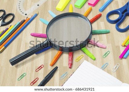 Image of black magnifier above colored crayons with school supplies on the floor