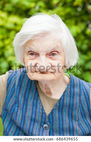 Portrait of an aged woman sitting outdoor in the garden on summertime