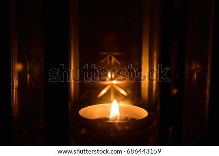 A candle in the lantern, a star pattern on the light