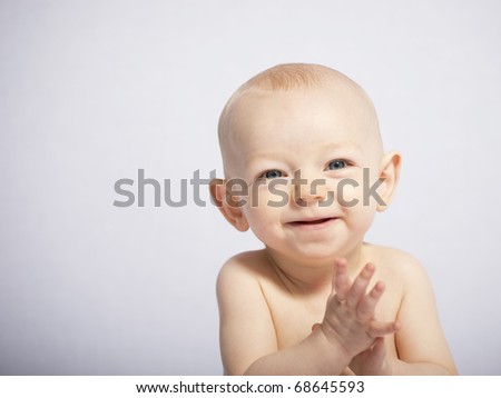 Happy toddler claps his hands on a white background