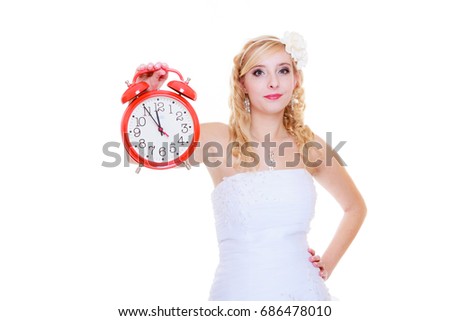 Wedding, waiting for celebration and proposal concept. Bride in white dress holding big red clock