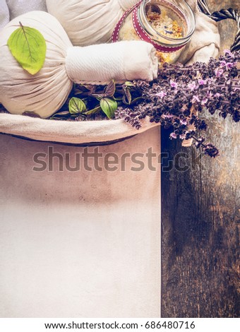 Spa or wellness background with close up of herbal massage compress balls , towel , salt and fresh herbs in basket on wooden background, top view