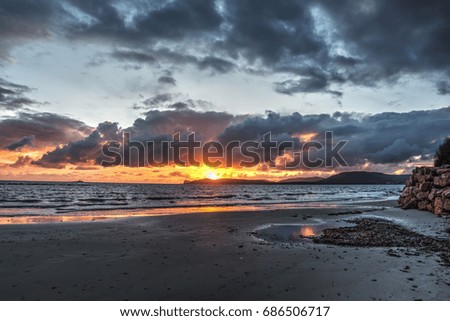 Shining sun and dark clouds at sunset. Sardinia, Italy