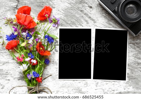 Retro camera and blank paper photo frames on wooden table with summer wildflowers. concept of remembrance and nostalgia in autumn. mock up