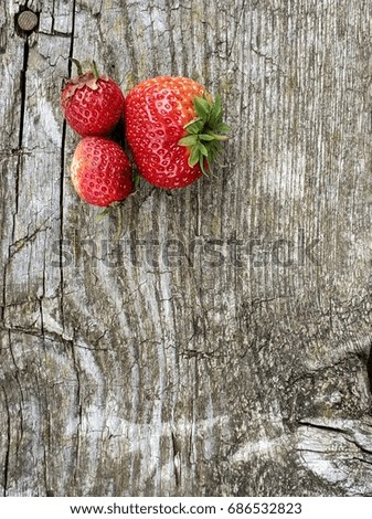Kitten plays with strawberries on a wooden background