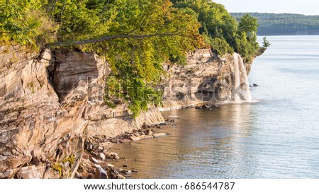 One tree grows out sideways from the cliff, while another tree balances precariously on an overhang, near Spray Falls, in Pictured Rocks National Lakeshore, on Lake Superior, near Munising, Michigan.