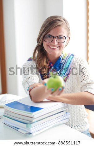 Female college students sitting on the desk with apple on a pile of books. Student. College