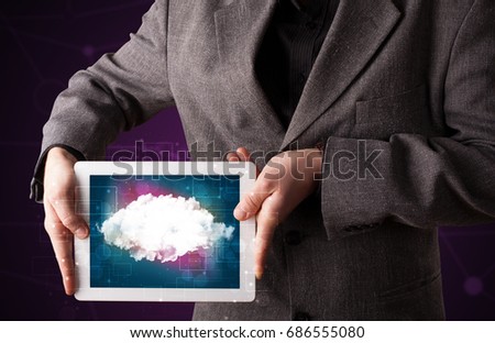 Casual businessman holding tablet with cloud icon and purple background