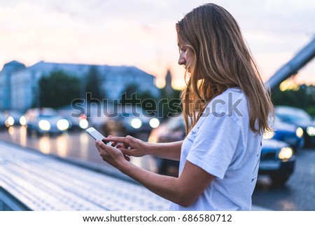 Hipster girl in white t-shirt holding smart phone in hands,Attractive young woman making selfie in the centre of the city, Tourist taking picture in the Moscow