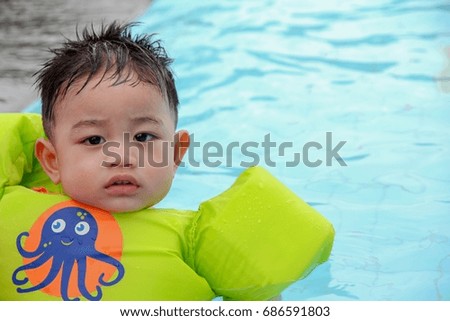 Asian baby wear life jacket in the pool , he learning to swim