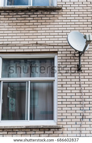 Light brick apartment building with dish antenna and windows