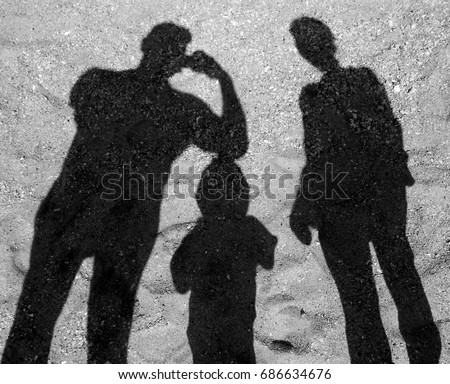 Shadows of a man, a woman and a child on the sand
