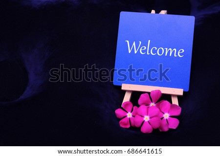 The text of Welcome on a board with flowers as a business concept.