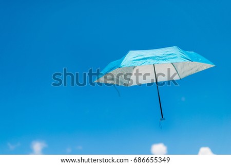A blue umbrella flying on a blue sky