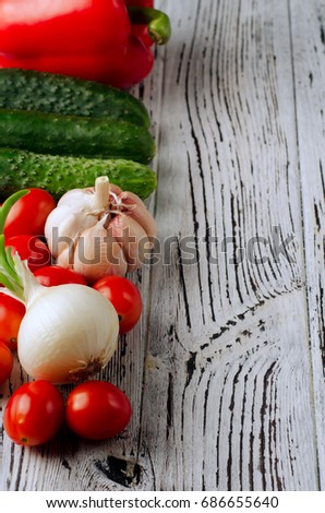 Whole fresh clean vegetables lined on a wooden surface. Stock for preparation of Greek salad. In a set of garlic, onions, cucumbers, cherry tomatoes, sweet peppers, paprika