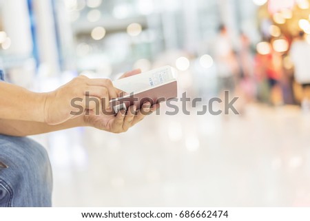 Man's hand hold passport showing immigration entry and departure stamps with beautiful bokeh at airport,selective focus,traveling concept,copy space.
