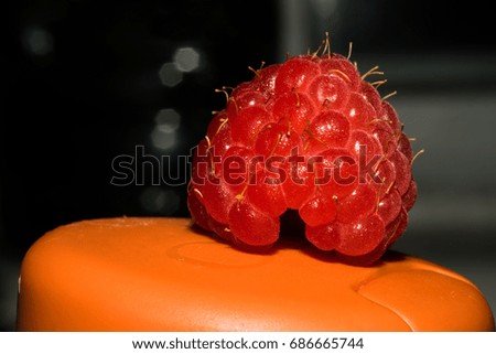 Bright red raspberries on an orange surface. Macro