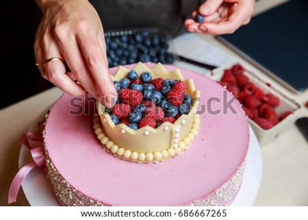 Pastry Chef decorating with berries delicious princess cake.