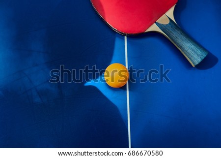 Orange ball place on the table with blue floor, Top angle view of Table Tennis paddle or Ping Pong racket Sport Equipment 