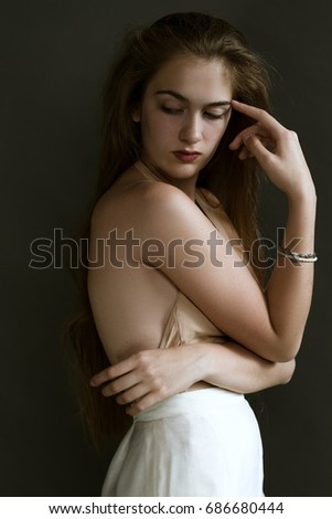 Art portrait of a beautiful girl with long hair on a dark background in the studio