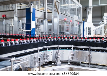 Bottling factory - Black juice bottling line for processing and bottling juice into bottles. Selective focus.  Royalty-Free Stock Photo #686690584