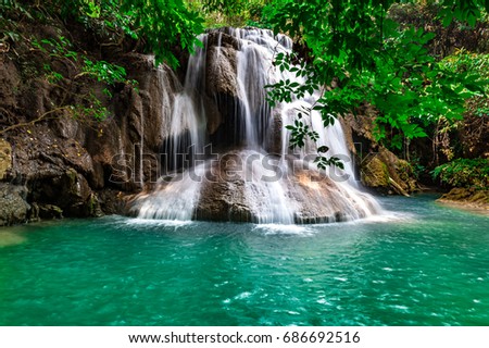 Soft waterfall, beautiful green water in a green tree forest on a tropical mountain at Erawan National Park, Thailand.