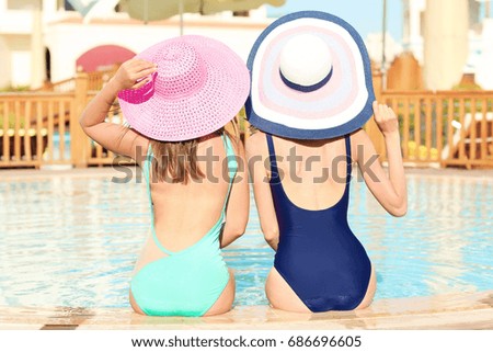Beautiful young women relaxing on edge of swimming pool