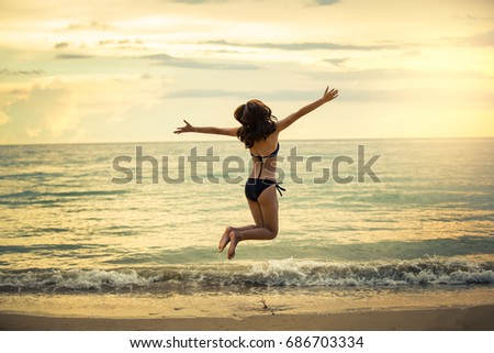 Happy Asian woman jumping on the beach. Summer vacation and freedom concept