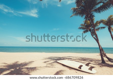Surfboard on tropical beach in summer. landscape of summer beach and palm tree with sea, blue sky background. Vintage color tone