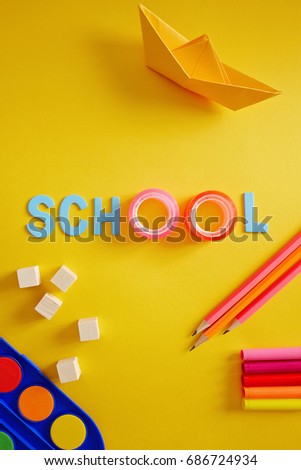 Back to school supplies and letters on yellow background. 