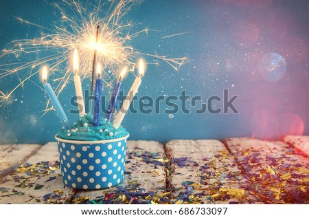 Birthday concept with cupcake and candles on wooden table.