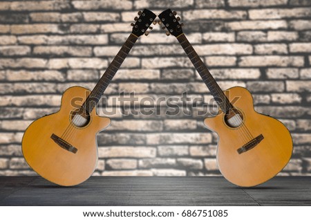 two acoustic guitar on the wooden floor against  brick wall background.