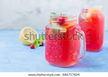 Summer Refreshment Berry Drink. Lemonade with raspberry and blackberry with lemon, mint in mason jar on blue stone table background. Copy space