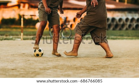 An action picture of an old ball and foot of a kid who is playing football for exercise.Low key style.