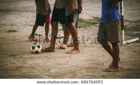 An action picture of an old ball and foot of a kid who is playing football for exercise.Low key style.